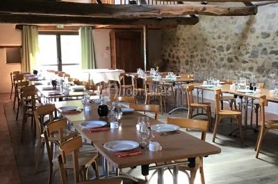 Arbre en fleurs roses devant un bâtiment en pierre avec une porte en bois, sous un ciel bleu clair.