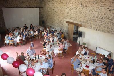 Arbre en fleurs roses devant un bâtiment en pierre avec une porte en bois, sous un ciel bleu clair.
