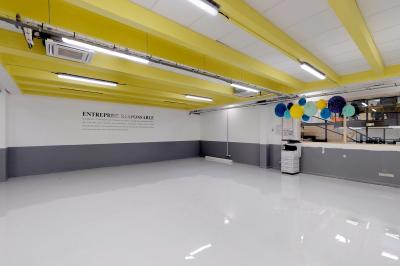 Salle de réunion lumineuse avec table en bois, chaises colorées, tableau blanc et grande fenêtre donnant sur l'extérieur.
