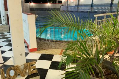 Un couple de mariés danse au centre d'une salle décorée, entouré d'invités applaudissant.