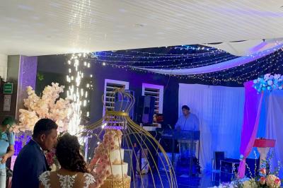 Un couple de mariés danse au centre d'une salle décorée, entouré d'invités applaudissant.