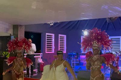 Un couple de mariés danse au centre d'une salle décorée, entouré d'invités applaudissant.