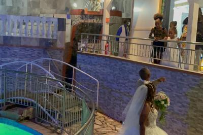 Un couple de mariés danse au centre d'une salle décorée, entouré d'invités applaudissant.