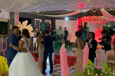 Un couple de mariés danse au centre d'une salle décorée, entouré d'invités applaudissant.