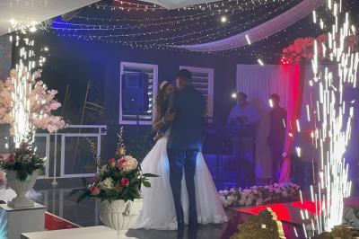 Un couple de mariés danse au centre d'une salle décorée, entouré d'invités applaudissant.