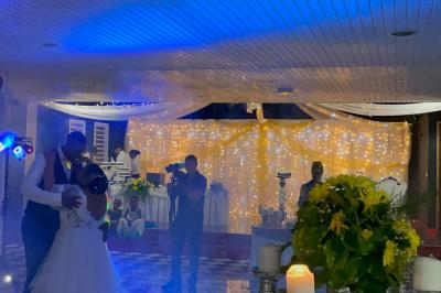 Un couple de mariés danse au centre d'une salle décorée, entouré d'invités applaudissant.