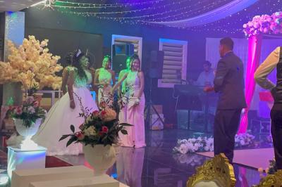 Un couple de mariés danse au centre d'une salle décorée, entouré d'invités applaudissant.