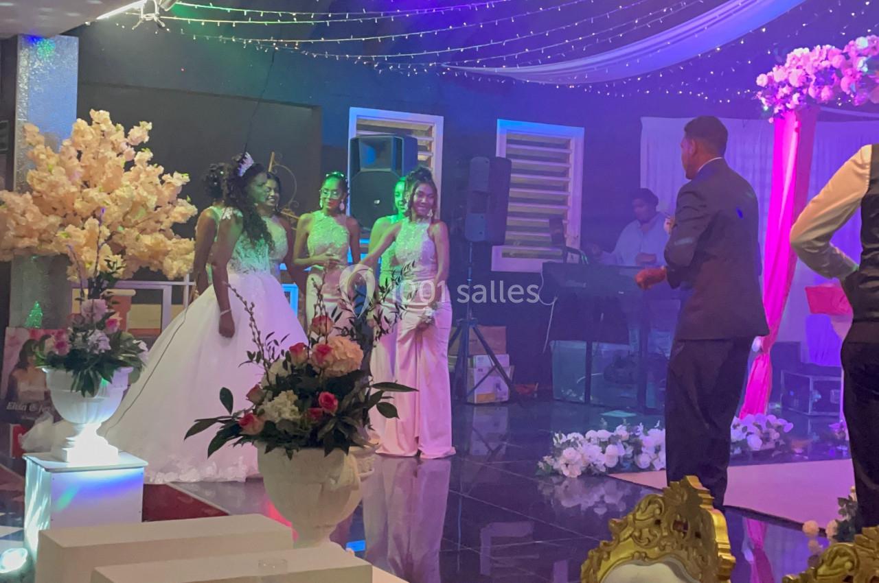 Des personnes en tenue de soirée discutent sur une piste de danse décorée avec des lumières et des fleurs.