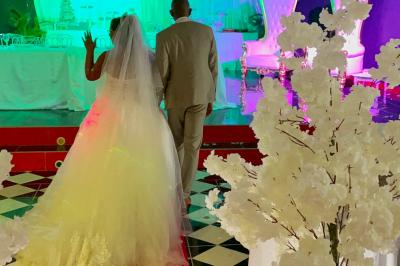 Un couple de mariés danse au centre d'une salle décorée, entouré d'invités applaudissant.