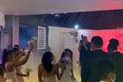 Un couple de mariés danse au centre d'une salle décorée, entouré d'invités applaudissant.