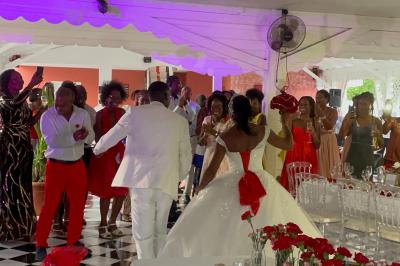 Un couple de mariés danse au centre d'une salle décorée, entouré d'invités applaudissant.