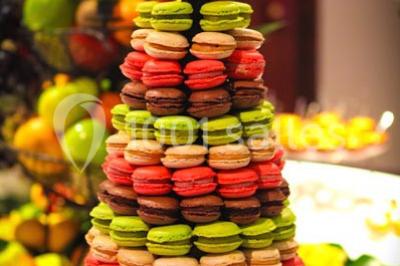 Table en bois décorée de fleurs colorées, verres, assiettes et couverts, installée en extérieur sous une tente.