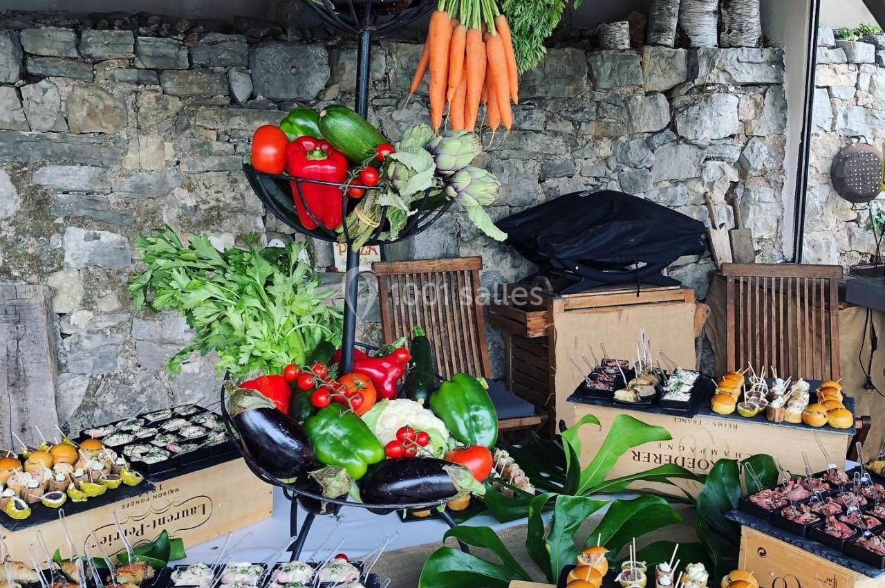 Présentoir de légumes frais et buffet de bouchées variées disposés sur des caisses en bois dans un cadre rustique.