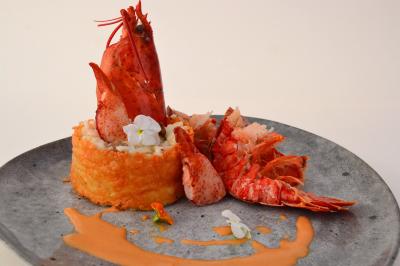 Table en bois décorée de fleurs colorées, verres, assiettes et couverts, installée en extérieur sous une tente.