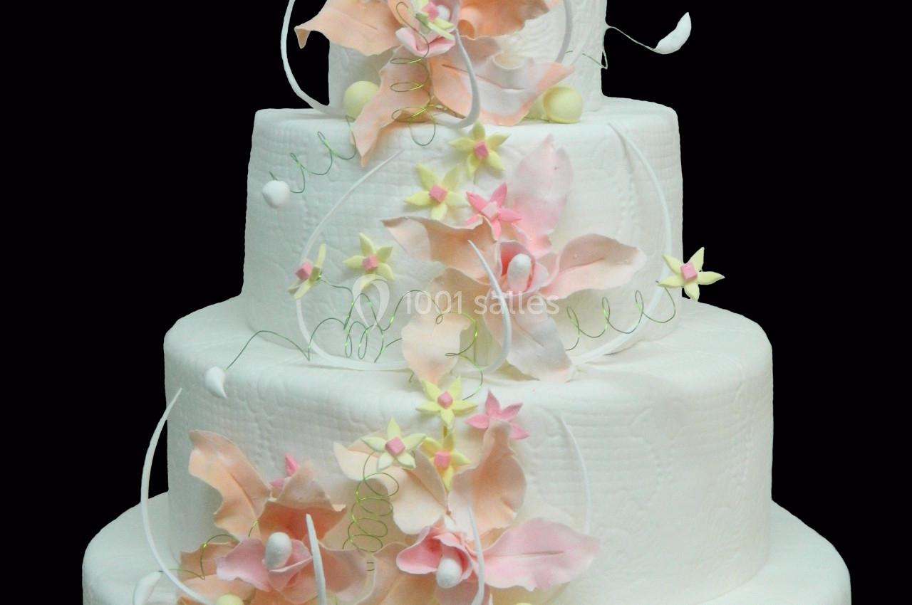 Gâteau de mariage à quatre étages décoré de fleurs en sucre roses et blanches avec des détails délicats.