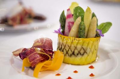 Allée décorée pour une cérémonie en plein air, entourée d'arbres, avec chaises en bois et rubans suspendus.