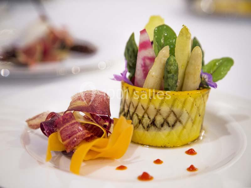 Assiette gastronomique avec légumes colorés dressés artistiquement, accompagnée de chips de légumes et de sauce.