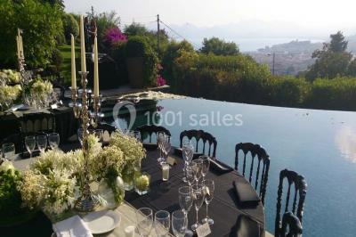 Allée décorée pour une cérémonie en plein air, entourée d'arbres, avec chaises en bois et rubans suspendus.