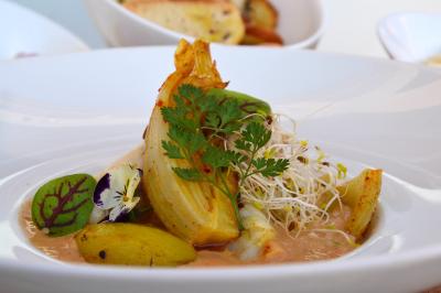 Allée décorée pour une cérémonie en plein air, entourée d'arbres, avec chaises en bois et rubans suspendus.