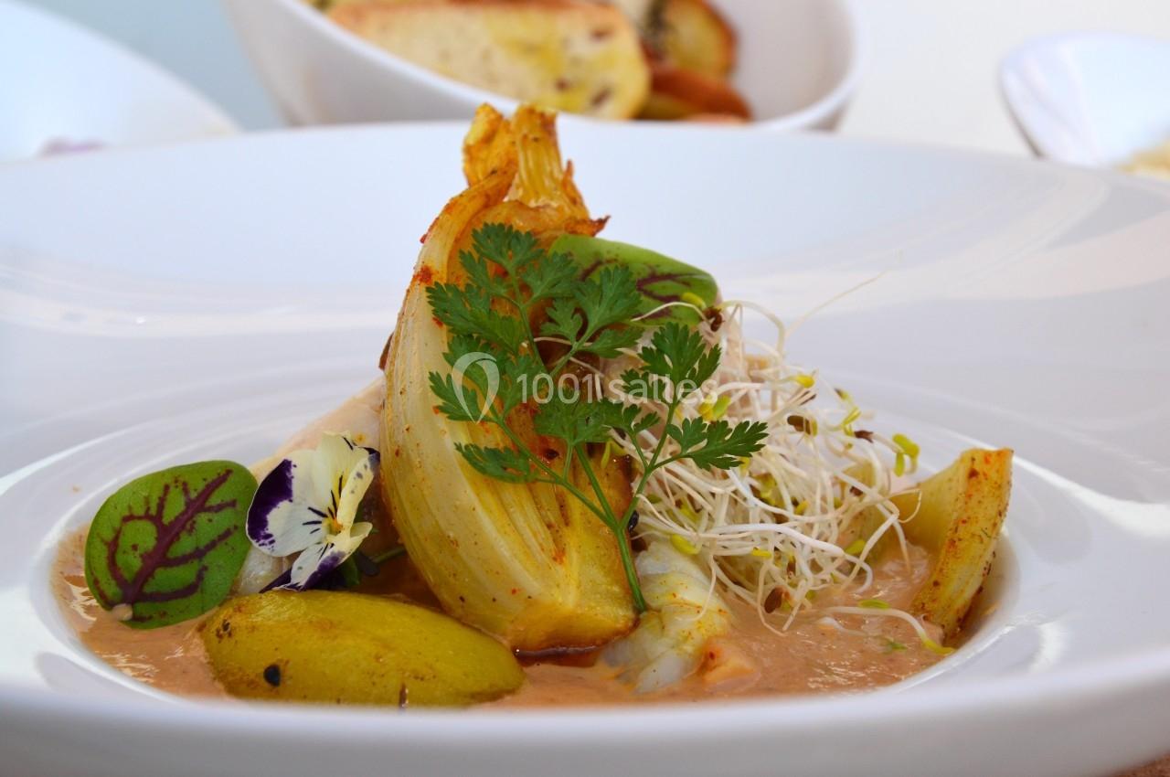 Assiette de légumes grillés avec sauce, décorée de pousses, herbes fraîches et fleurs comestibles.