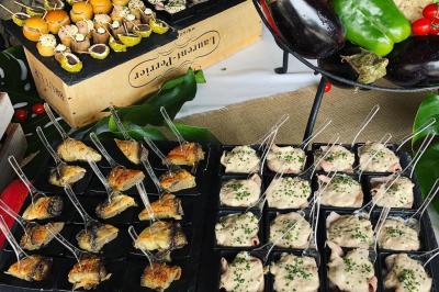 Allée décorée pour une cérémonie en plein air, entourée d'arbres, avec chaises en bois et rubans suspendus.