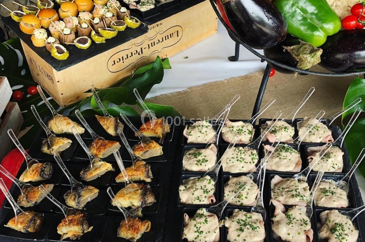 Plateau de bouchées apéritives variées présentées sur des caisses en bois, entourées de légumes frais.