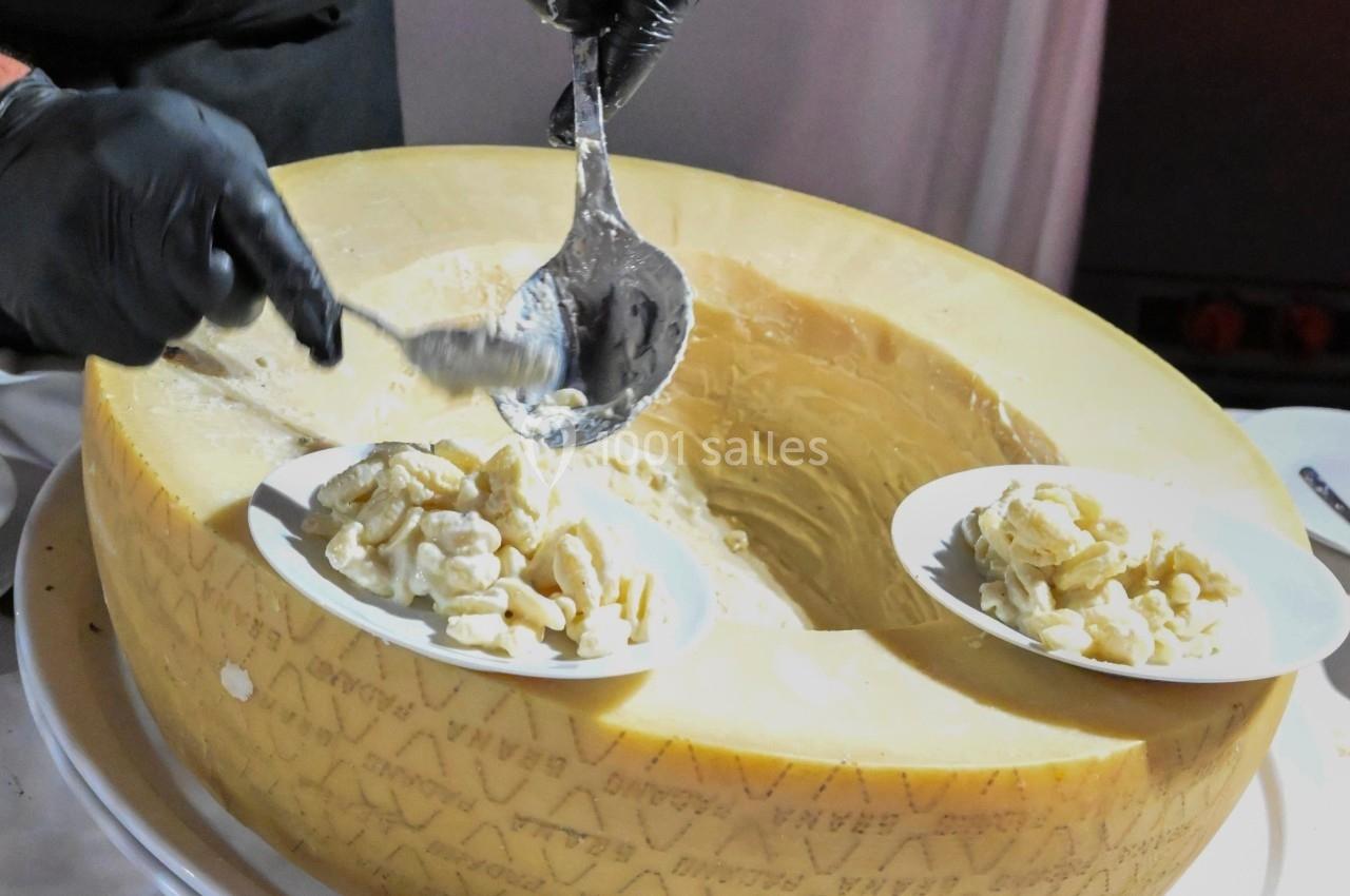 Un cuisinier sert des pâtes crémeuses directement dans une meule de fromage.