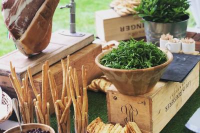 Allée décorée pour une cérémonie en plein air, entourée d'arbres, avec chaises en bois et rubans suspendus.