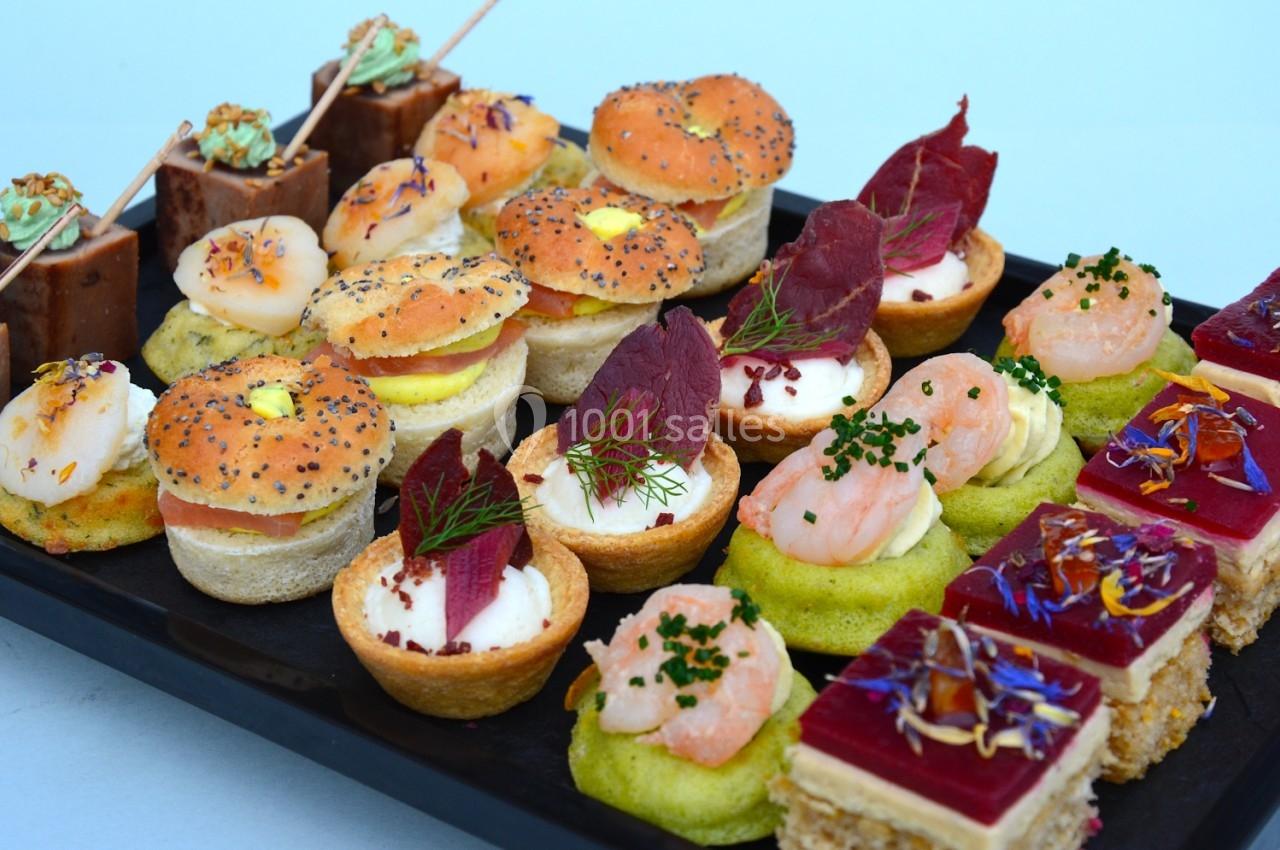 Plateau de bouchées apéritives variées avec mini-burgers, tartelettes, canapés et desserts colorés.