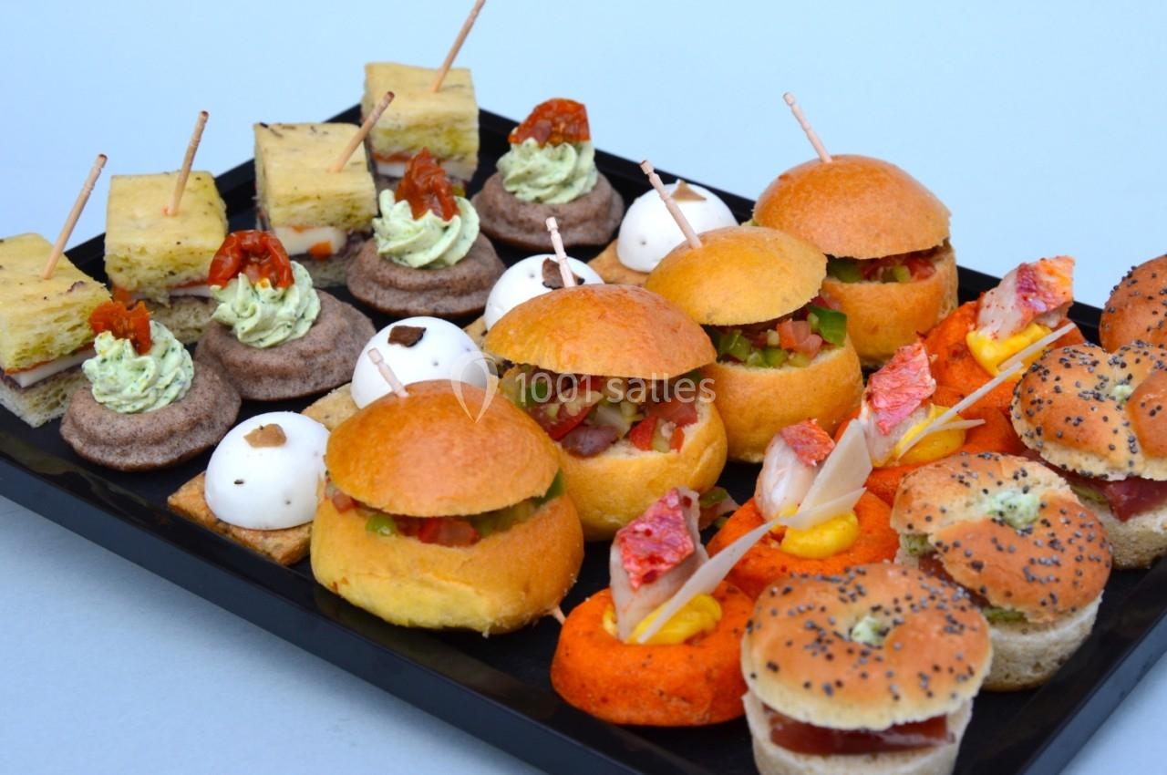 Plateau de mini-sandwichs variés et bouchées apéritives colorées présentées sur un plateau noir.