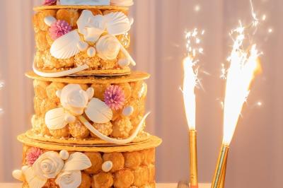 Allée décorée pour une cérémonie en plein air, entourée d'arbres, avec chaises en bois et rubans suspendus.