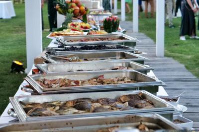 Allée décorée pour une cérémonie en plein air, entourée d'arbres, avec chaises en bois et rubans suspendus.