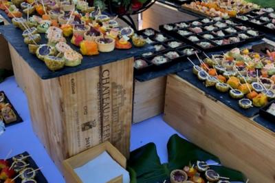 Allée décorée pour une cérémonie en plein air, entourée d'arbres, avec chaises en bois et rubans suspendus.