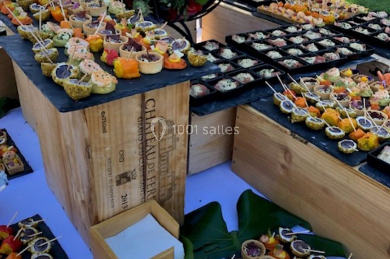 Buffet en plein air avec une présentation soignée de bouchées apéritives variées sur des plateaux et caisses en bois.