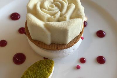 Allée décorée pour une cérémonie en plein air, entourée d'arbres, avec chaises en bois et rubans suspendus.