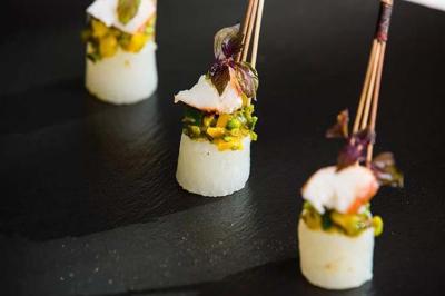 Personne utilisant une trancheuse rouge pour couper de la charcuterie dans un environnement professionnel.