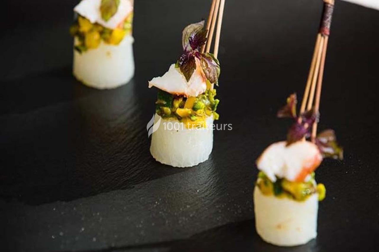 Bouchées gastronomiques composées de poisson, légumes et herbes, présentées sur une assiette noire.
