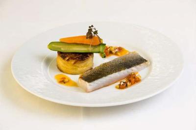 Personne utilisant une trancheuse rouge pour couper de la charcuterie dans un environnement professionnel.