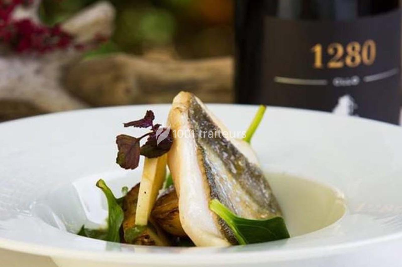 Filet de poisson grillé servi avec légumes verts et jeunes pousses dans une assiette blanche, bouteille de vin en arrière…