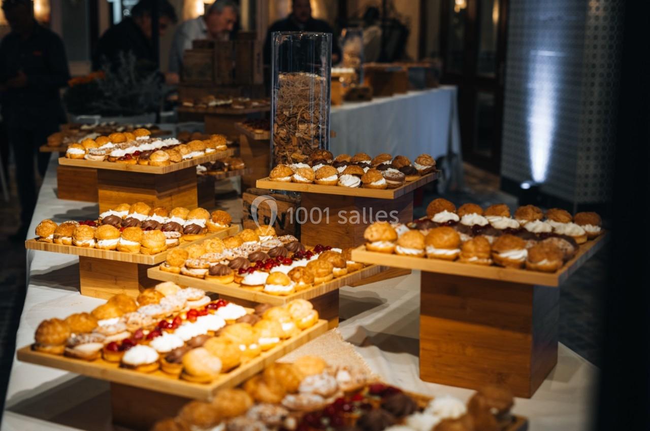 Plateaux en bois garnis de pâtisseries variées, disposés sur des tables dans un espace intérieur éclairé.