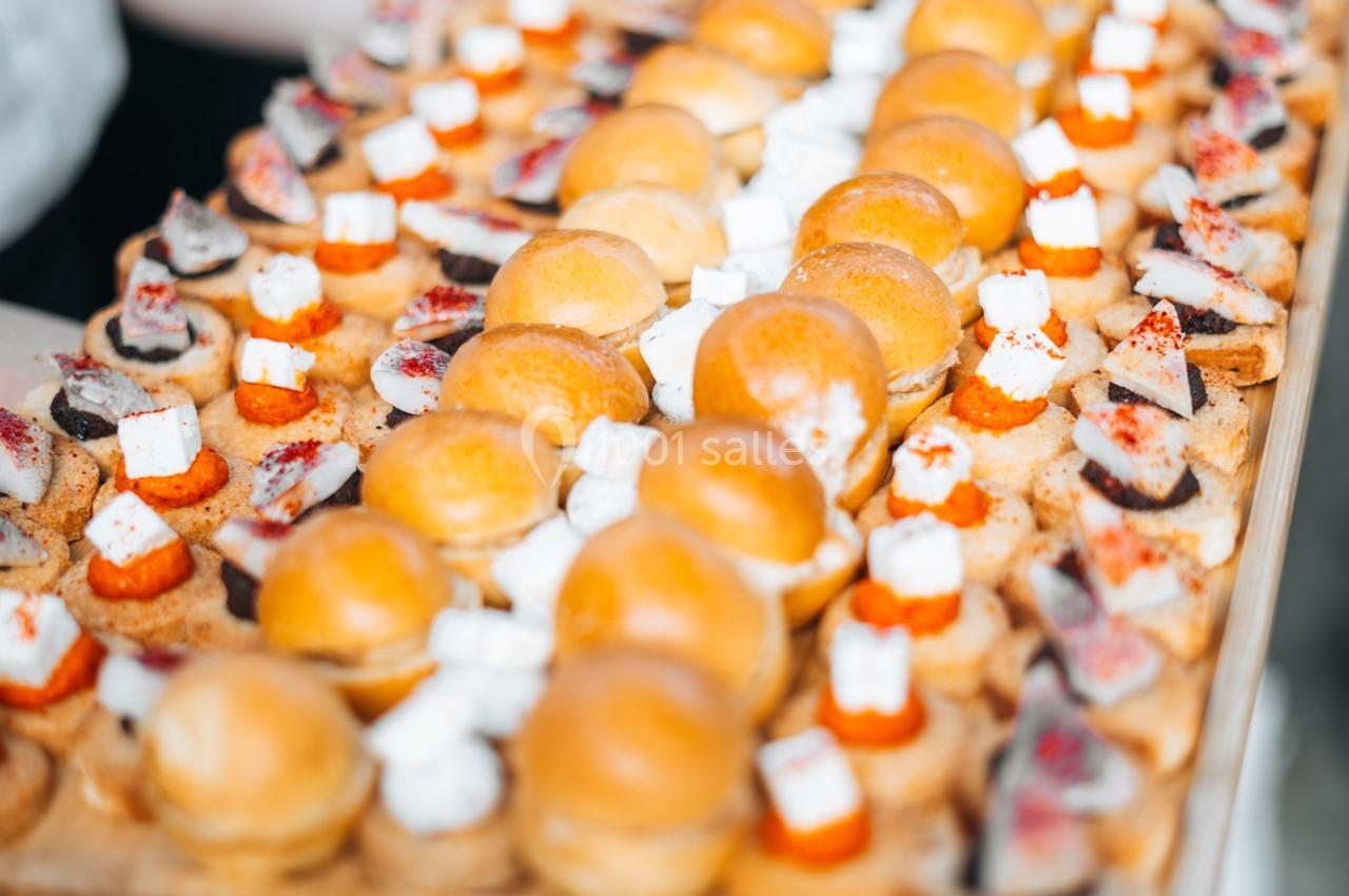 Plateau de bouchées apéritives variées comprenant des mini-burgers, des toasts garnis et des amuse-bouches.