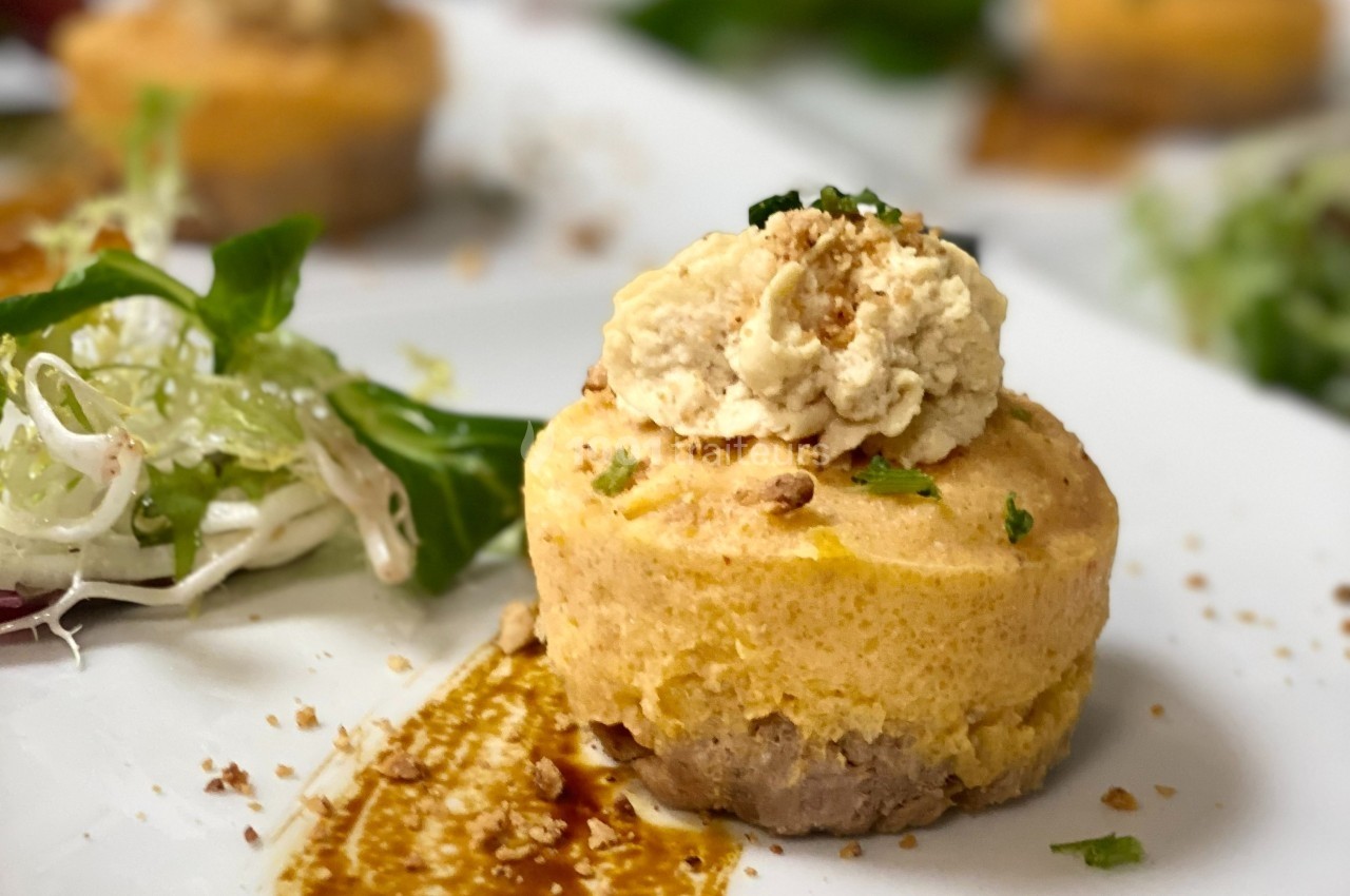 Flan salé garni de crème et éclats de noix, accompagné de salade verte et d'une sauce en décoration.