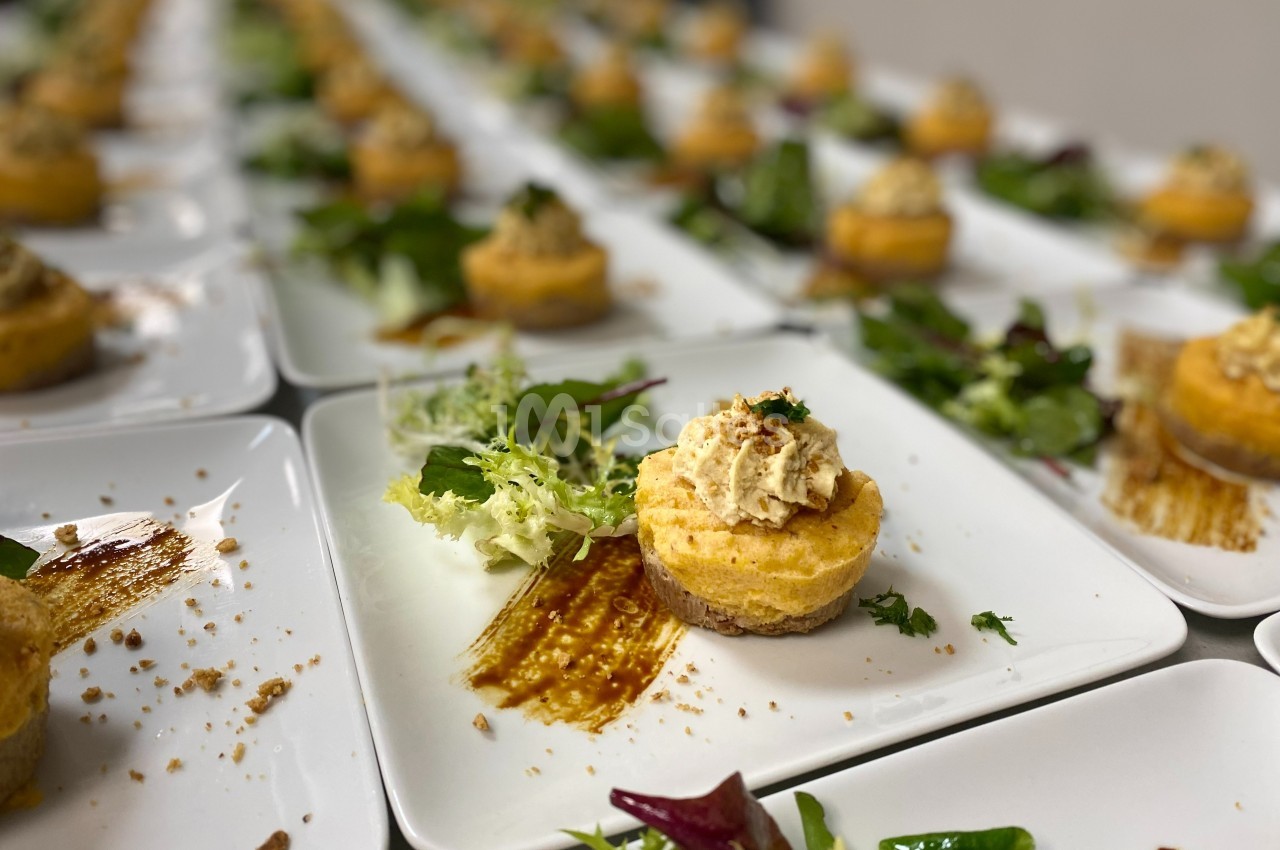 Assiettes dressées avec des mini-cheesecakes salés, salade verte et filet de sauce en décoration.