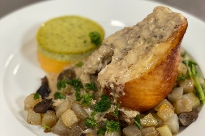 Portion de viande braisée servie dans une petite coupelle, garnie de pousses rouges.