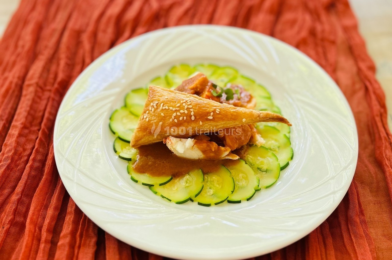 Assiette garnie de tranches de concombre disposées en cercle, surmontées de pâte feuilletée et d'une garniture en sauce.