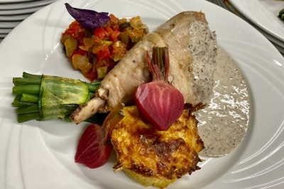 Portion de viande braisée servie dans une petite coupelle, garnie de pousses rouges.