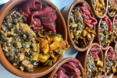 Portion de viande braisée servie dans une petite coupelle, garnie de pousses rouges.