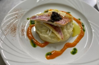 Portion de viande braisée servie dans une petite coupelle, garnie de pousses rouges.
