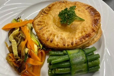 Portion de viande braisée servie dans une petite coupelle, garnie de pousses rouges.