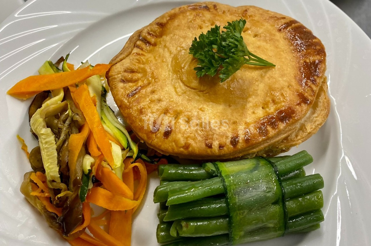 Tourte dorée garnie de persil, accompagnée de haricots verts, courgettes, carottes et chou sautés.